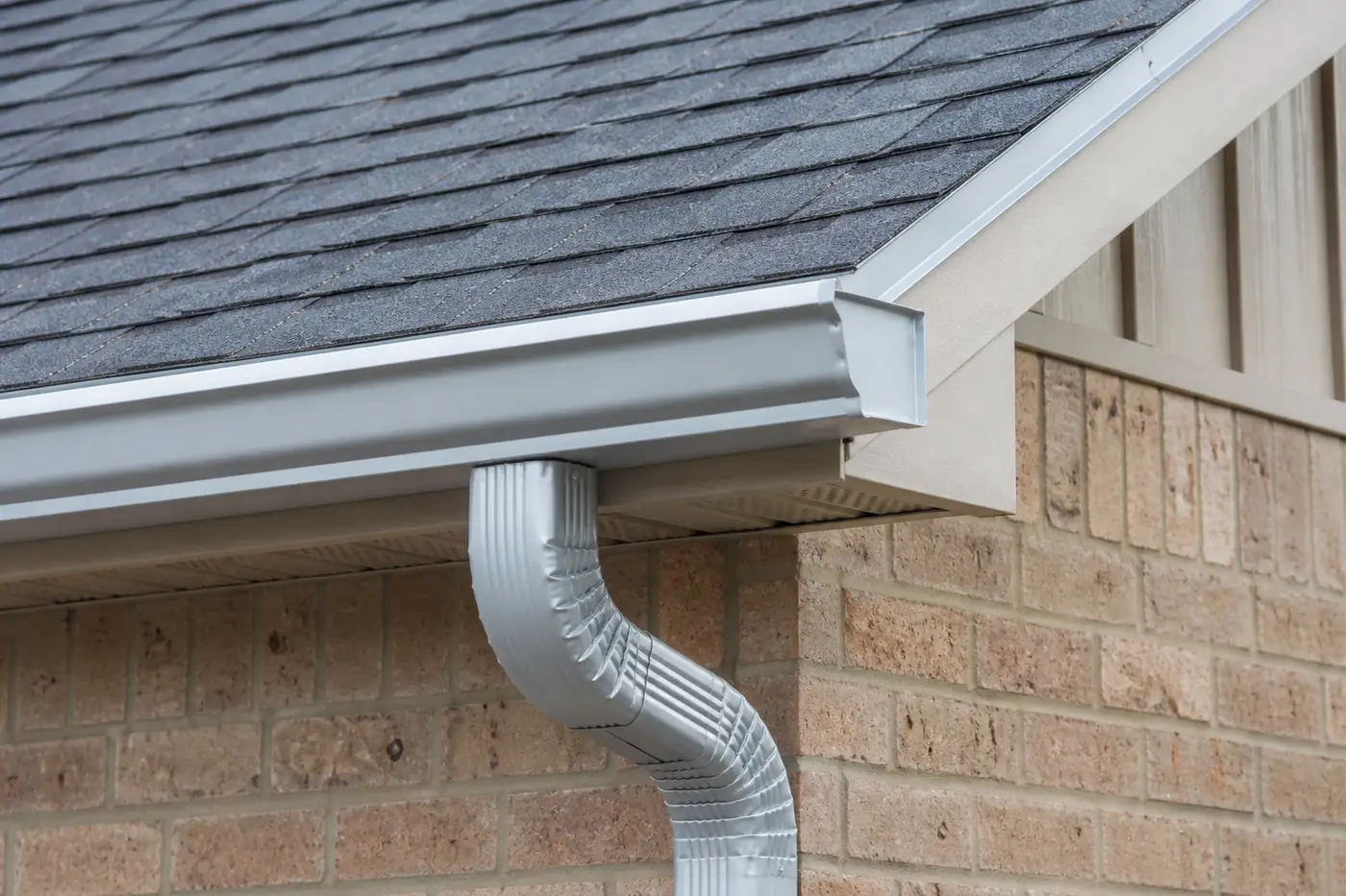 Aluminum gutter and downspout along a residential roof eave
