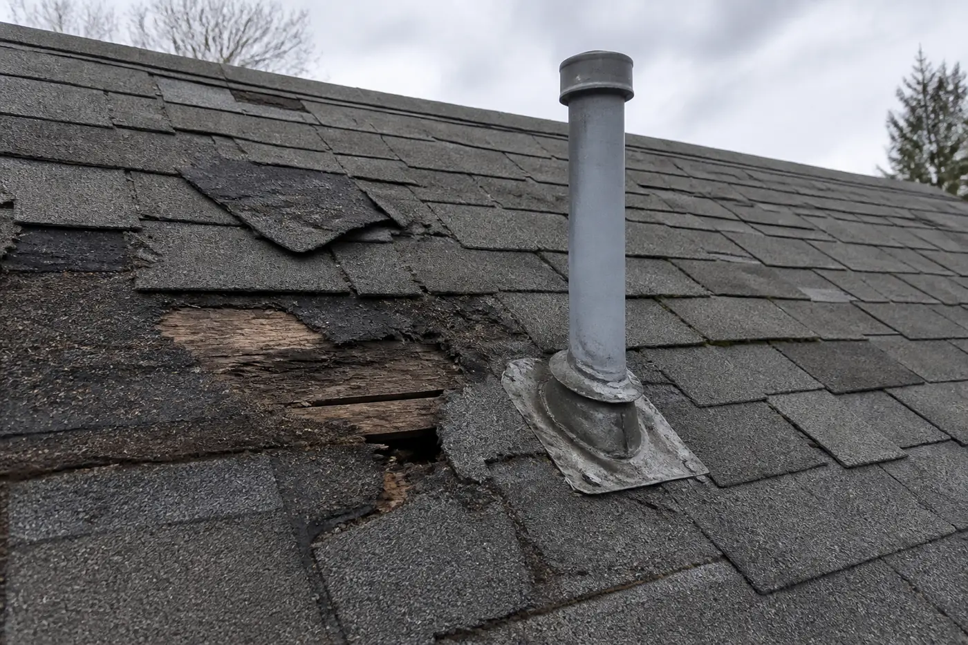 Damaged shingles and flashing before repair